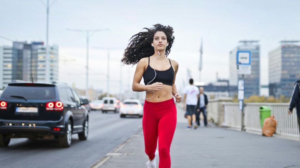 Focused woman running on a city street, symbolizing daily discipline, self-improvement, and personal growth through simple habits.