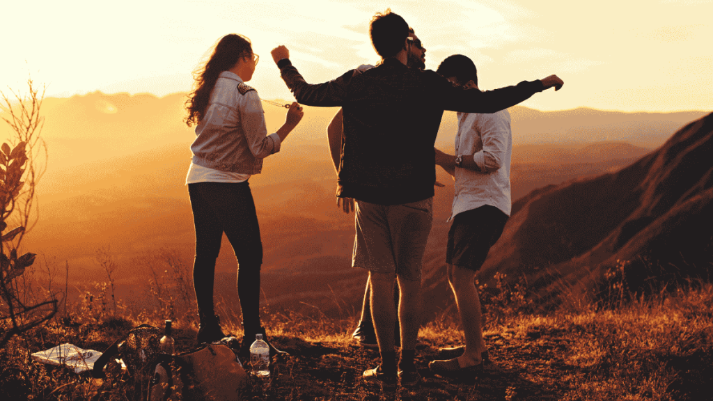 Group of friends enjoying sunset on a hilltop after a hike, representing balanced living and mindful connection.